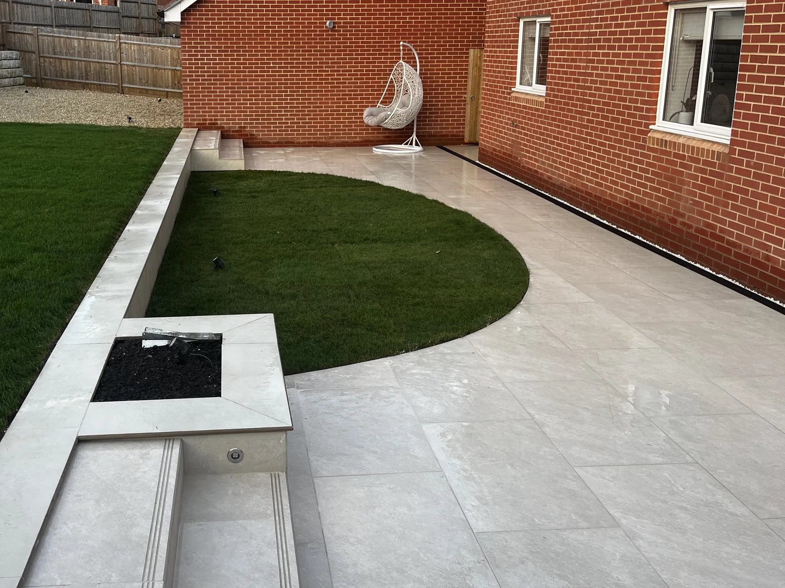 HLS project photograph showing paving, artificial lawn edges and retaining-wall detailing